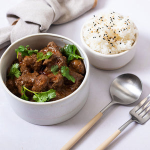 Bowl of beef curry with rice on a white table